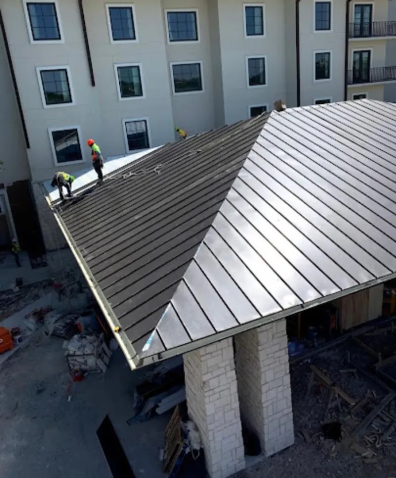 Crew installing standing seam metal roof panels on a commercial project in Windsor